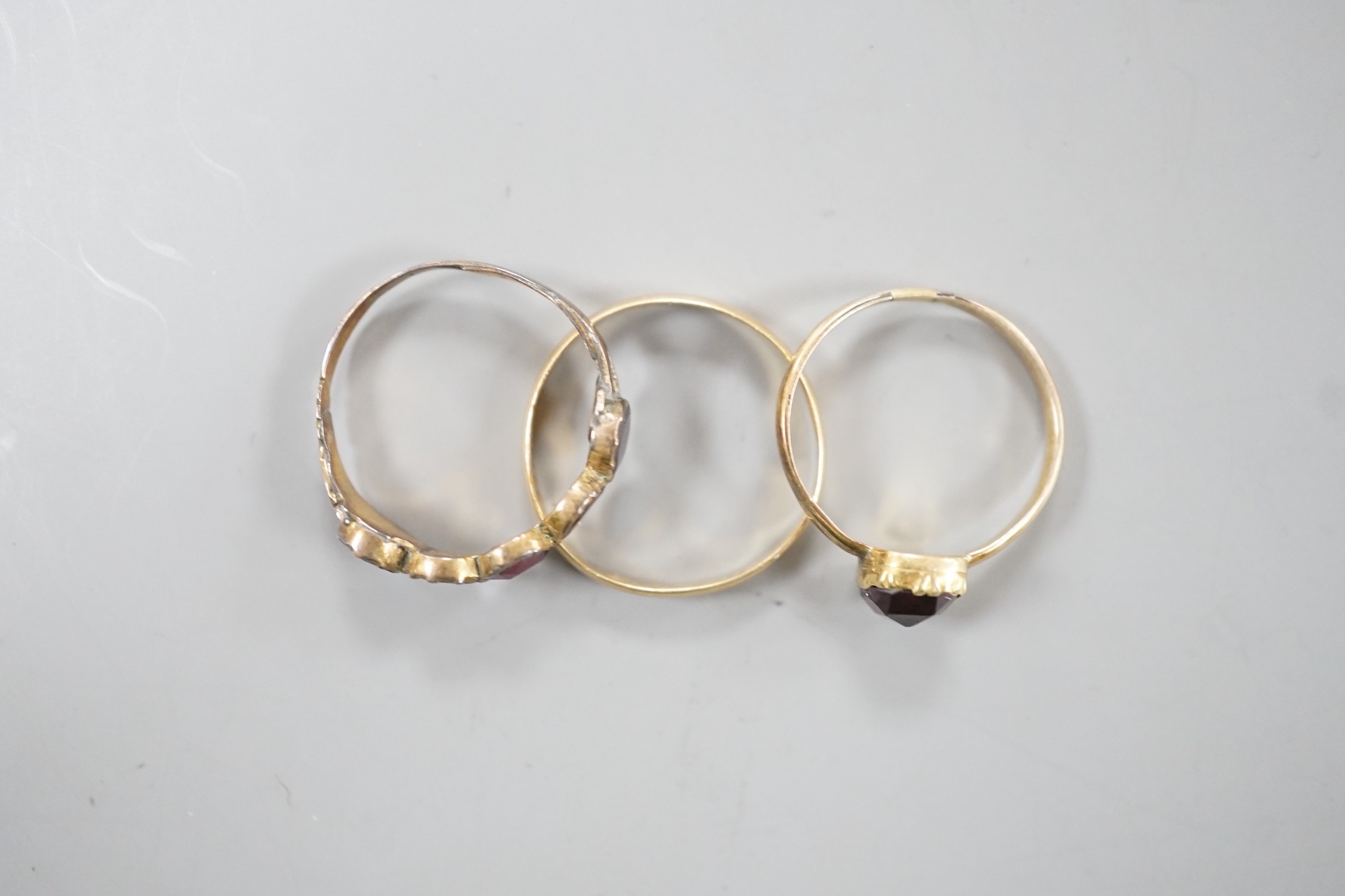 Two 19th century yellow metal and garnet set rings, including five stone half hoop, size J and single stone, size G/H and a yellow metal posy ring inscribed 'Vertue Gaineth Glory', gross weight 2.9 grams.